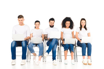 Obraz premium multicultural cheerful group of young people using laptops isolated on white