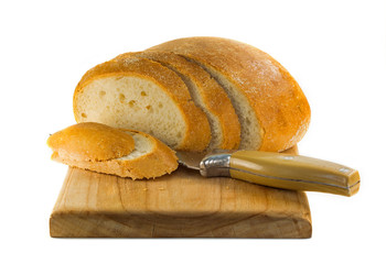loaf of bread with chopped slices and a knife on a white background. a loaf of round white bread on...