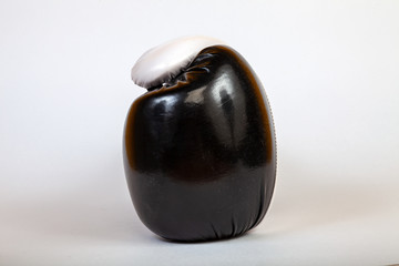 Close-up on a black side turned boxing glove for a blow on a white isolated background. A tool for punishment.