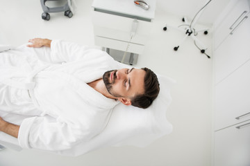 Obraz premium Top view of calm man relaxing in spa salon and smiling