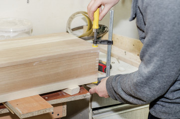 Gluing the wooden box, clamping with clamps. Work in the carpentry workshop. Wooden crafts. Fastening parts.