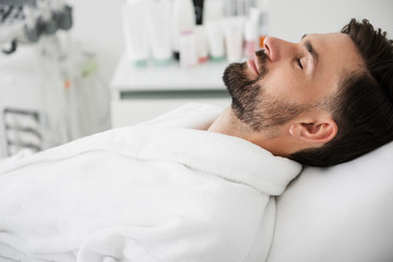 Peaceful man closing his eyes in spa salon