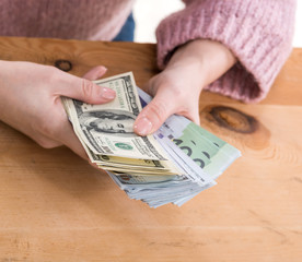 Close up of woman hands holding  us dollar and euro money