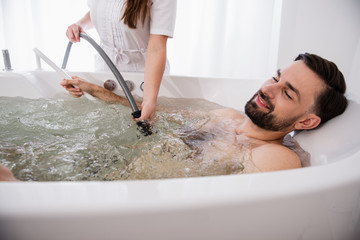 Bearded man relaxing in hydro massage bathtub and closing his eyes