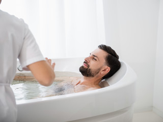 Calm man relaxing in hydro massage bathtub and smiling