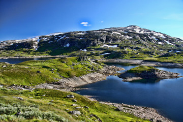 Fototapeta na wymiar The beautiful alpine lake in Scandinavia with remnants of snow nearby