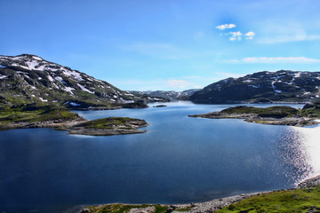 Fototapeta na wymiar The beautiful alpine lake in Scandinavia with remnants of snow nearby