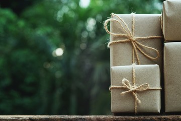 Stack of simple eco friendly gift box package wrap with brown paper in old wooden table background, green present concept