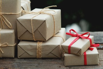 Stack of simple eco friendly gift box package wrap with brown paper in old wooden table background, green present concept