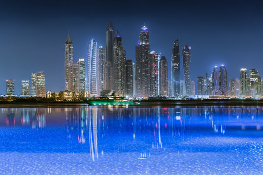 Die moderne Skyline der Dubai Marina bei Nacht mit Reflektionen der Lichter im Wasser