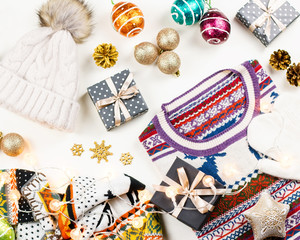 Christmas mood composition with Christmas sweater, hat, presents and lights. Winter concept flat lay, top view