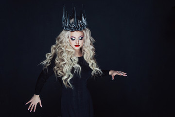 Portrait of a Gothic Princess. Beautiful young blonde woman in metal crown and black cloak.