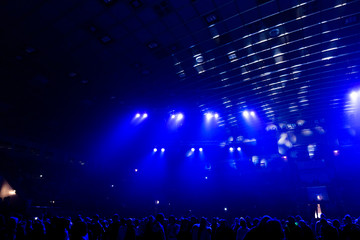 Concert crowd in the rays of blue spotlights.