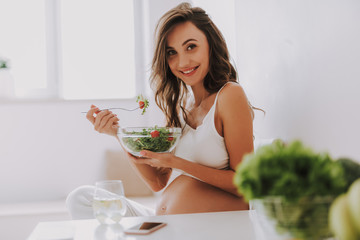 Expectant mother tasting salad and holding big bowl in hands