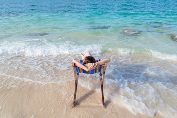Young lady relaxing in a chair on a beach at sunny day