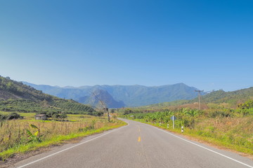Scenic highway route 1148, view on the road around with green meadow, mountain and blue sky background, Tham Sakoen National Park, Nan, northern of Thailand.