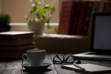 A cup of coffee in the workplace on a wooden table.