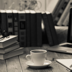 A cup of coffee in the workplace on a wooden table.