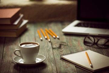 A cup of coffee in the workplace on a wooden table.