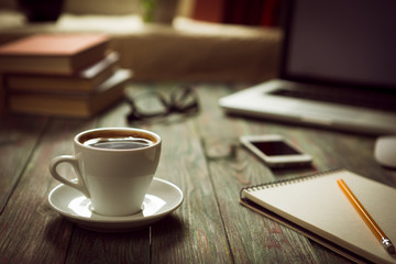 A cup of coffee in the workplace on a wooden table.