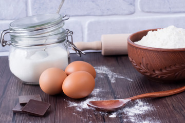 Products and objects for baking chocolate cake on dark wooden table. Concept of home baking.