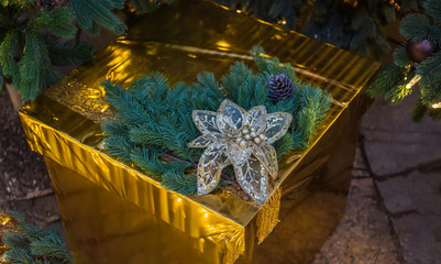 Christmas gold box with gifts. Golden balls and illuminated garland with flashlights.