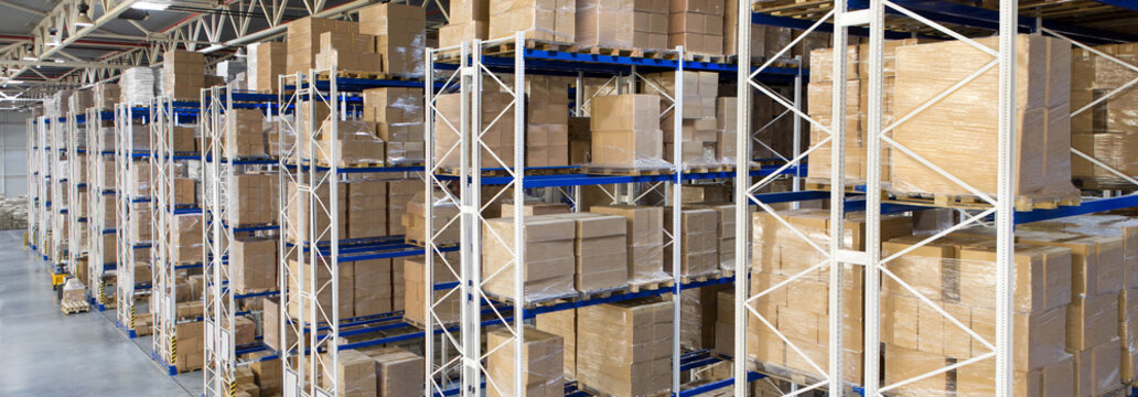 Boxes with goods on shelves in a large distribution warehouse with metal racking storage system