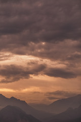 Beautiful golden sunset over peaks of mountains. Charming nature background. Vertical color photography.