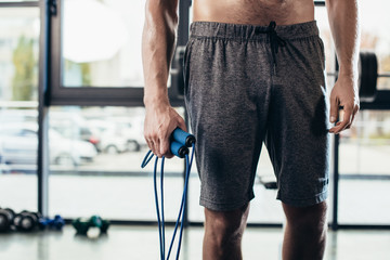 mid section of shirtless sportsman holding jumping rope in gym - obrazy, fototapety, plakaty