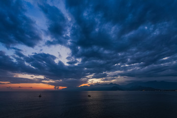 Tourists travelling by small ship in scenic marine background. Beautiful sunset sunny sea water, mountains, cloudy fluffy sky, sailing yacht. Horizontal color photography.