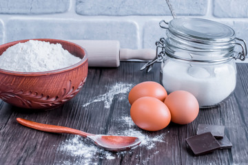 Products and objects for baking chocolate cake on dark wooden table. Concept of home baking.