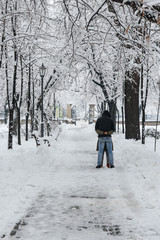 Long snow-covered alley of the park, lovers hugging on the alley