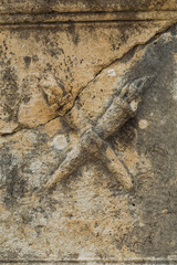 Real ancient olympic symbols sutted in stony wall of ancient architecture found during excavations of ancient ruins. Vertical color photography.