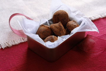 Chocolate truffles in tin box on red background with ribbon - 240026711