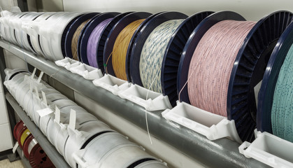Industrial warehouse cable reels, coils with wound wire fiber optics. Fragment inside modern...