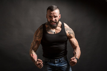 Uomo muscoloso e tatuato con faccia molto arrabbiata e muscoli in tensione