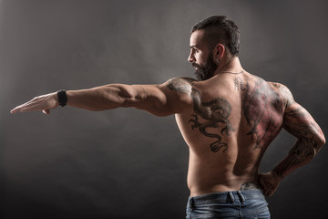 Uomo muscoloso e tatuato in posa plastica