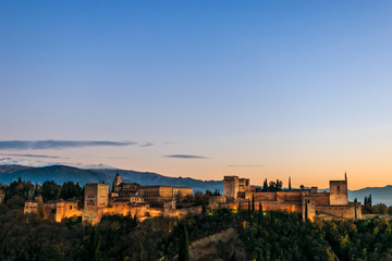 Alhambra Palace in Granada, Andalucia, Spain. Sierra Nevada mountains at the background. Golden hour at sunset. Space for text on the top