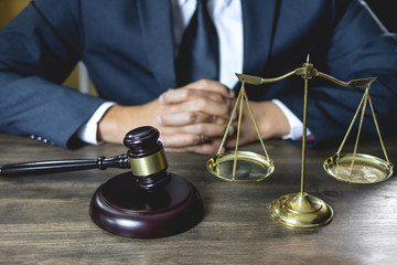 Legal law, advice and justice concept, male lawyer or notary working on a documents and report of the important case and wooden gavel, balance on table in courtroom