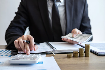 Businessman accountant counting money and making notes at report doing finances and calculate about cost of investment and analyzing financial data, Financing Accounting Banking Concept