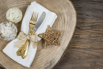Gold festive cutlery and napkin on wooden background.