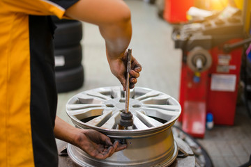 repair mechanic worker with light alloy car wheel disk rim