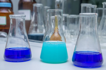 Laboratory glassware with multi-colored liquid on table. Chemical analysis