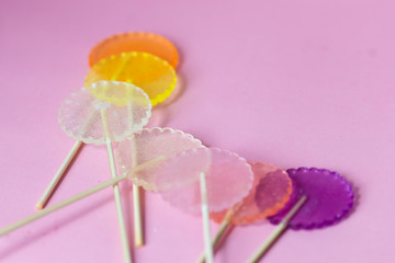Multi-colored transparent candy on a pink background with empty space, for children 