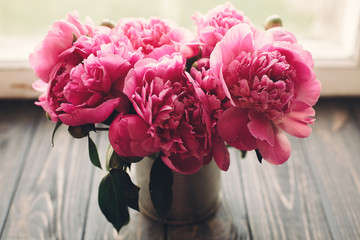 lovely pink peonies bouquet on rustic dark wooden background at window light, space for text. top view. floral greeting card. happy mothers day. spring image. shabby chic concept © sonyachny