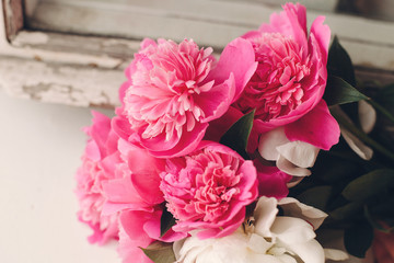 lovely pink peonies at rustic old white wooden window in light, space for text. top view. floral greeting card. happy mothers day or valentines. rural country image. shabby chic
