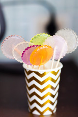 multi-colored lollipops on a pink background in a paper golden cup