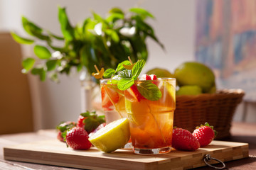 Refreshing summer drink with lemon, strawberry and mint on wooden table