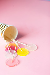 multi-colored lollipops on a pink background in a paper golden glass with copyspace