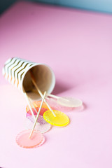 multi-colored lollipops on a pink background in a paper golden glass with copyspace